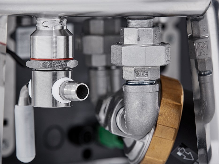 Nærbilde av metallbeslag og ventiler koblet til rør på Speidel 20L #Braumeister PLUS, med synlige muttere, skiver og hvite slanger for optimal temperaturkontroll ved automatisert brygging.