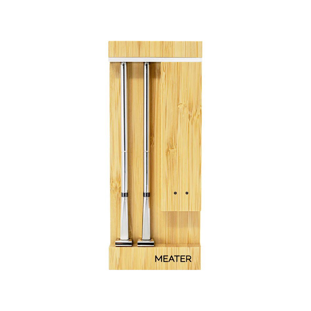 En ladeblokk i bambus merket Traeger holder to Meater Pro Duo - WiFi steketermometer i rustfritt stål.