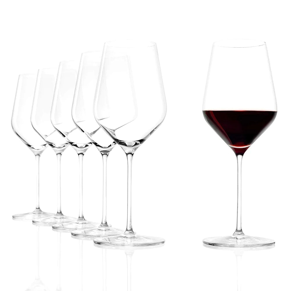 Seks STARlight Red Wine vinglass 510 ml fra Stölzle Lausitz er stilt opp på en hvit bakgrunn; fem er tomme, og ett til høyre er fylt med rødvin, noe som illustrerer deres elegante krystallglasshåndverk.