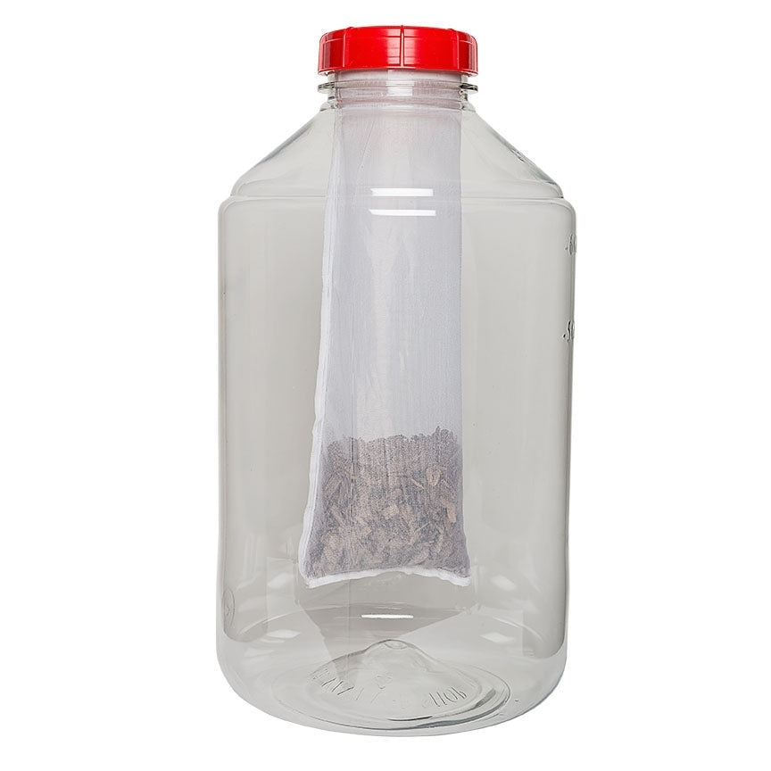 En stor, klar plastkrukke med rødt skruelokk inneholder et MonsterMesh-filter til FerMonster (300 mikron) fra The Vintage Shop, med tørket plantemateriale inni.