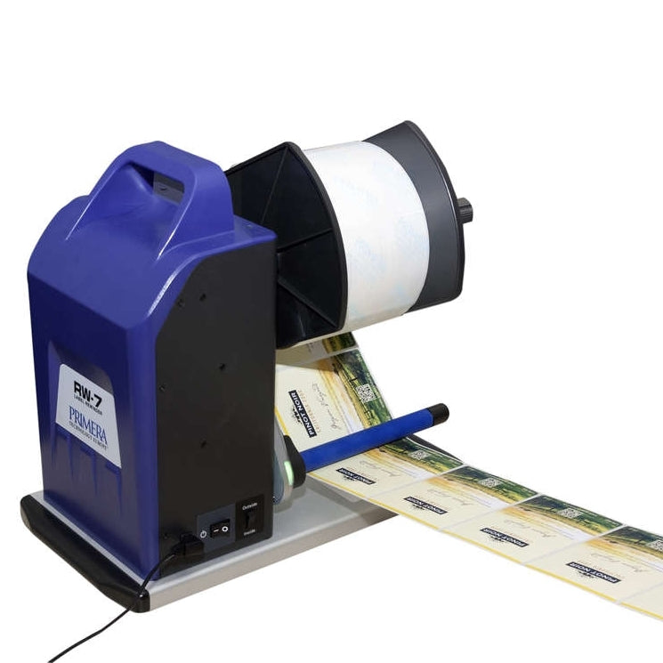 En blå og svart Primera RW-7 Rewinder - Oppruller for etiketter (Bestillingsvare) vikler trykte produktetiketter på en spole.