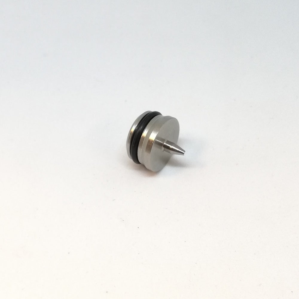 En Piercer til uKeg fra GrowlerWerks, med en liten metallisk kropp med en sentral spiss spiss, sirkulær base og to svarte O-ringer av gummi nær toppen, vist på en vanlig hvit bakgrunn.