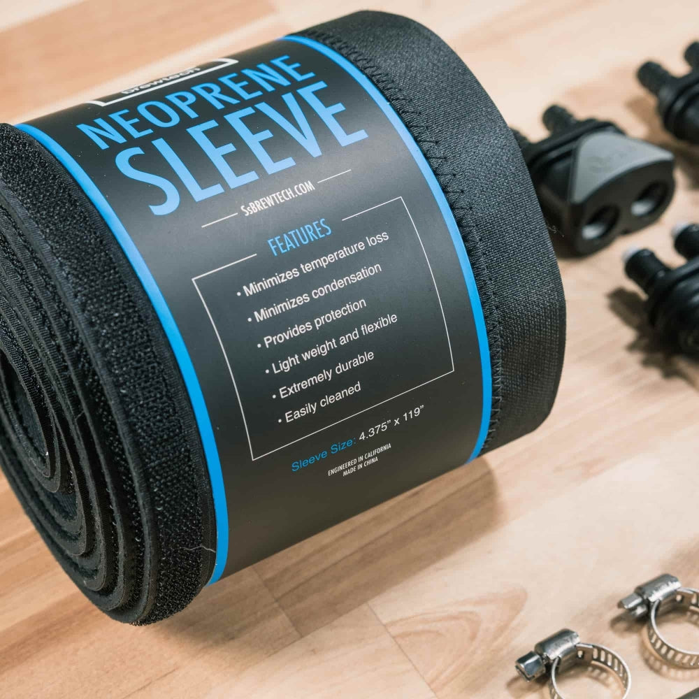 En sammenrullet neoprenhylse med en blå etikett ligger på en treflate ved siden av metallklemmer, svarte plastbeslag og Ss Brewtech FTSS One Quick Disconnect Kit.
