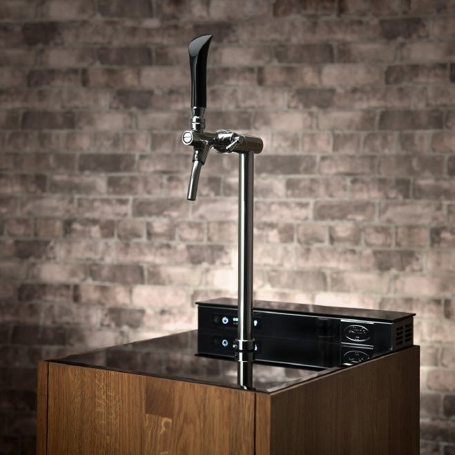 Et Lindr PYGMY Pro Kitchen-øltappsystem fra Lindr er installert på en trebenk med en murvegg som bakteppe.