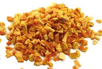 En haug med tørkede oransje og gule gulrotbiter i terninger blandet med Brewshop Appelsinskall søt 50g på hvit bakgrunn.