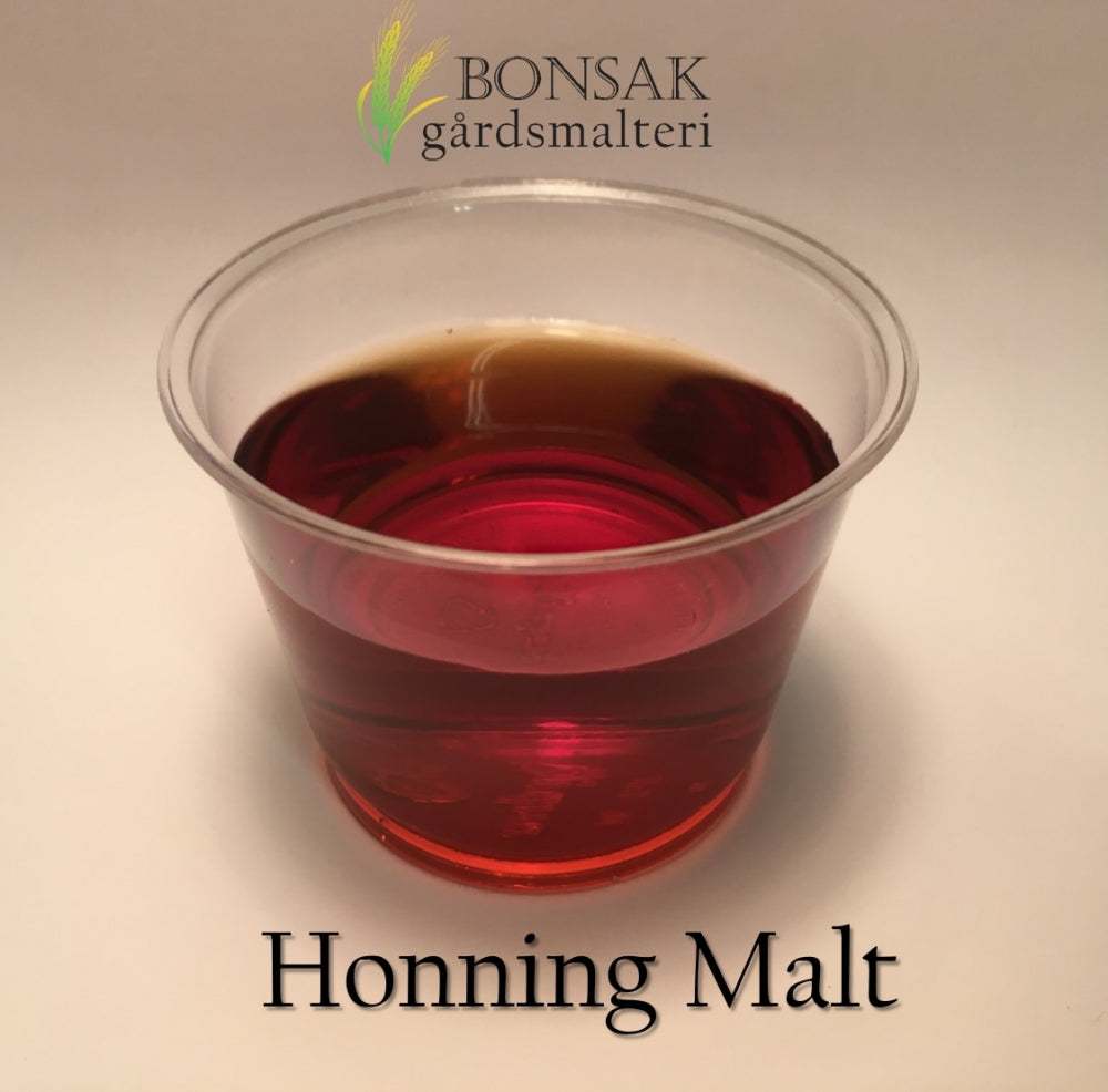 En klar plastkopp med ravfarget væske er avbildet. Over er "Bonsak Gårdsmalteri". Under: "Bonsak Gårdsmalteri": Honning Malt (40 EBC) 100G - laget av Bonsak Gårdsmalteri med norsk malt og rike honningtoner for en unik smak.