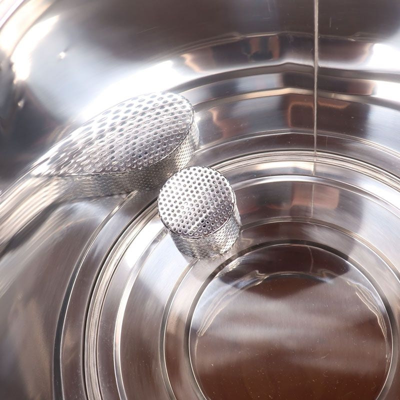 To teksturerte metallsylindere er plassert inne i en Brewolution Nytt bunnfilter til Brewster Beacon 40L & 70L rustfritt stål beholder med litt vann i bunnen.