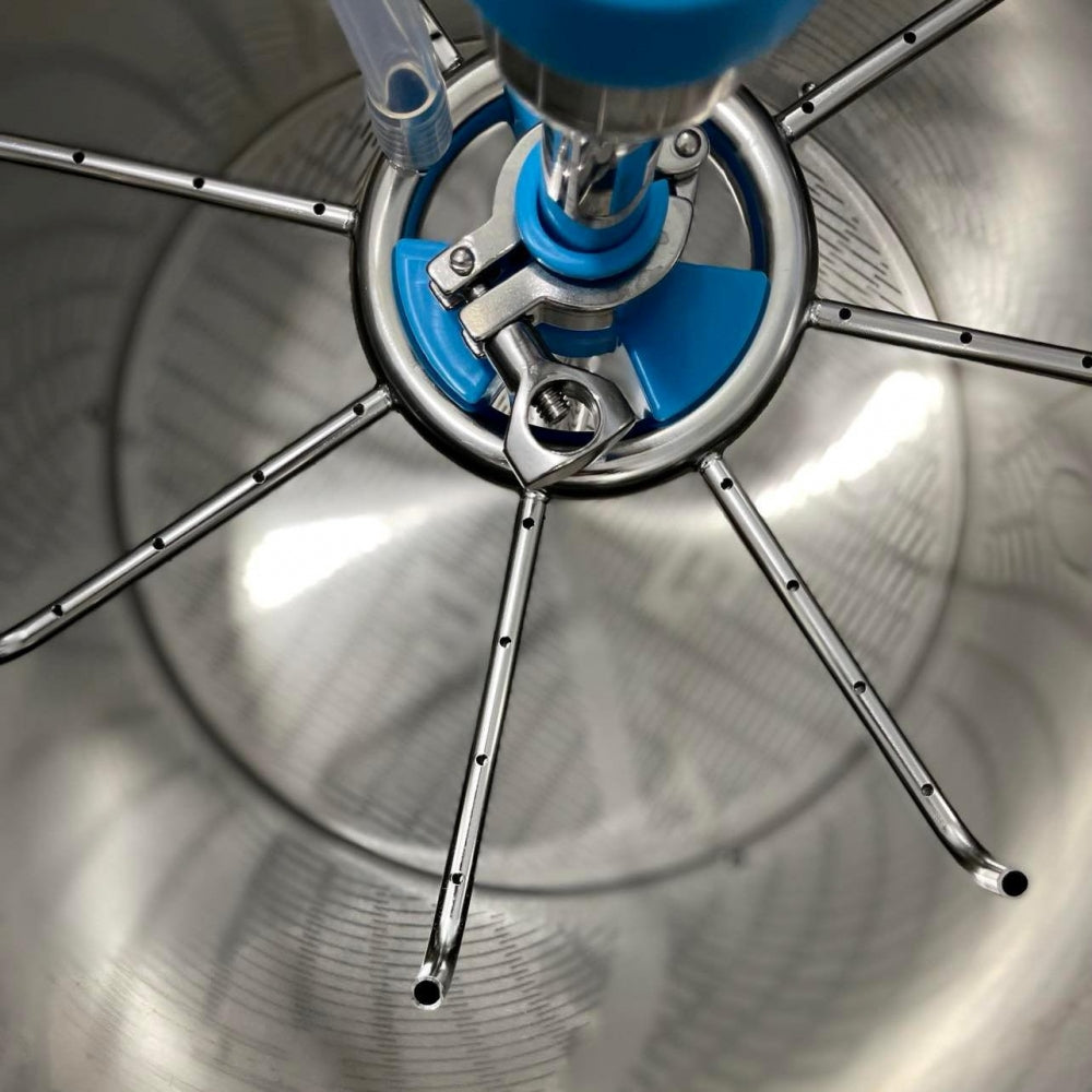 Nærbilde av Brewtools Sirkulasjonsmanifold L installert i en Brewtools B150Pro, vist inne i en stor stålskål med flere metallarmer og et blått nav i midten.