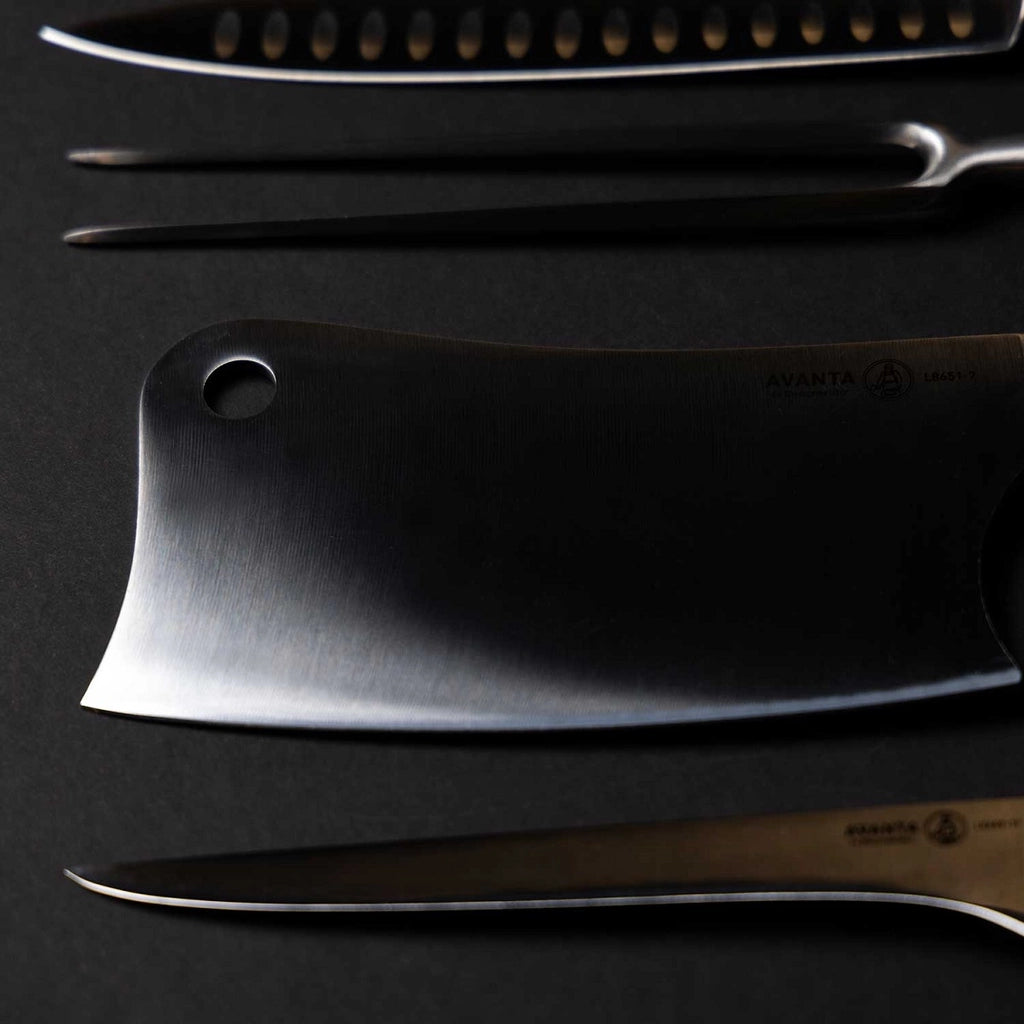 Nærbilde av tre redskaper i rustfritt stål fra Messermeister Avanta BBQ Knivsett - kjøttkniv, skjæregaffel og påleggskniv - plassert på en mørk flate.