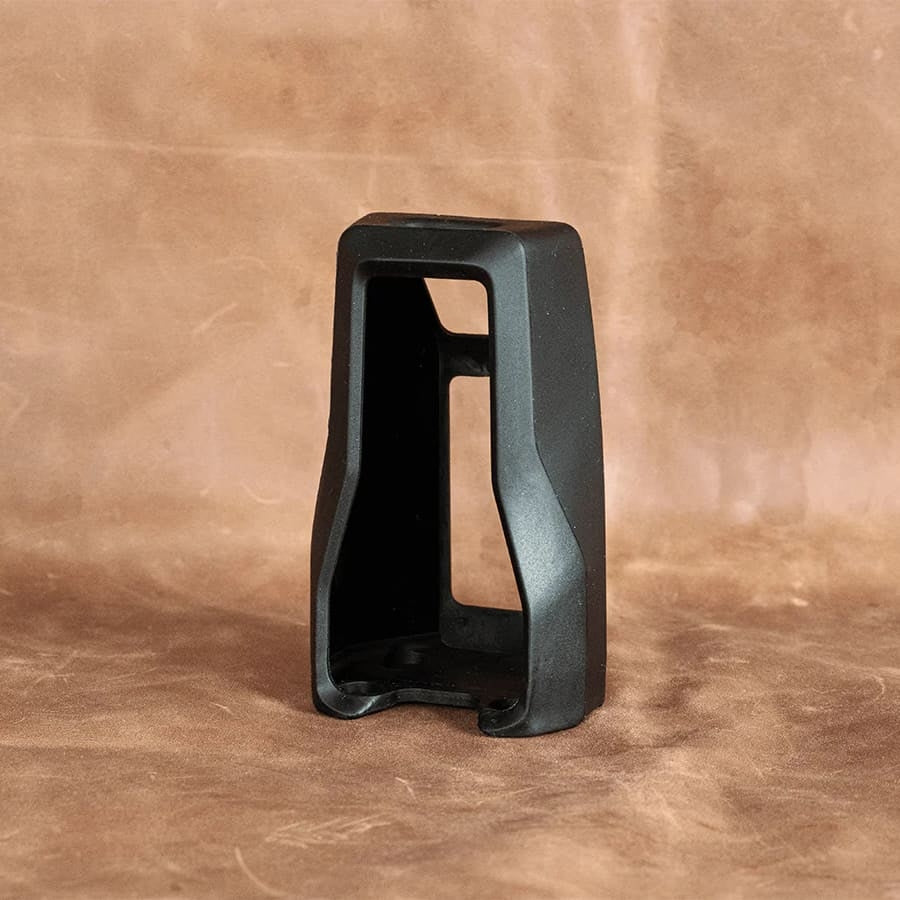 Anton Paar EasyDens Beskyttelsesdeksel - Beskyttelsesdeksel er et svart plastdeksel med et åpent rektangulært design, vist stående på en brun teksturert overflate mot en brun bakgrunn.