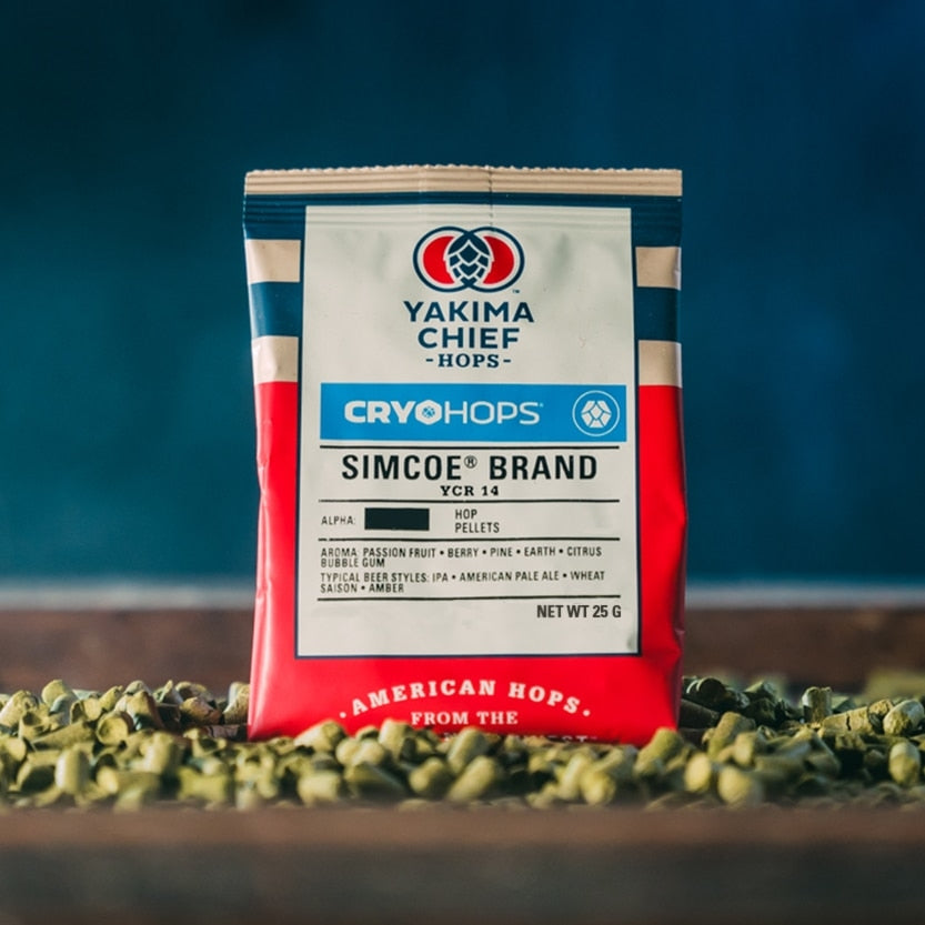 En 25 g-pakke med Yakima Chief Simcoe Cryo Hops (23 %) står oppreist på et bord, med løse Simcoe Cryo Hops-pellets spredt rundt.