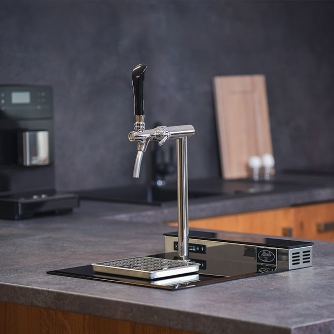 Lindr PYGMY Pro Kitchen øltappsystem fra Lindr, utstyrt med dryppbrett, står på en moderne kjøkkenbenk ved siden av en kaffemaskin og skjærebrett i tre - ideelt for ethvert tappetårn kjøkkenoppsett.