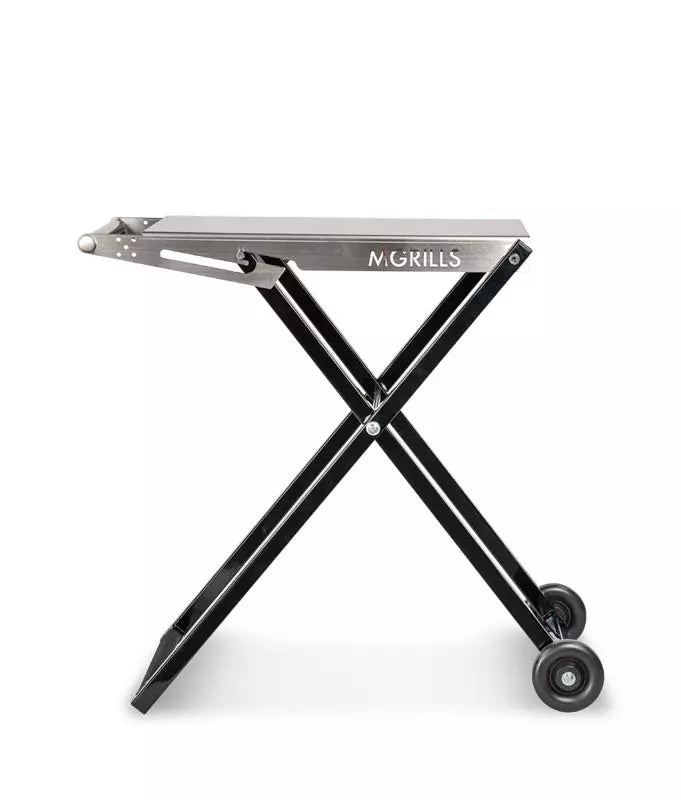 C4 Folding Cart er et rustfritt stålgrillbord med hjul for M16 fra M Grills, som har et bærbart, sammenleggbart design med svarte X-formede ben og to hjul. M Grills logo er plassert på siden.