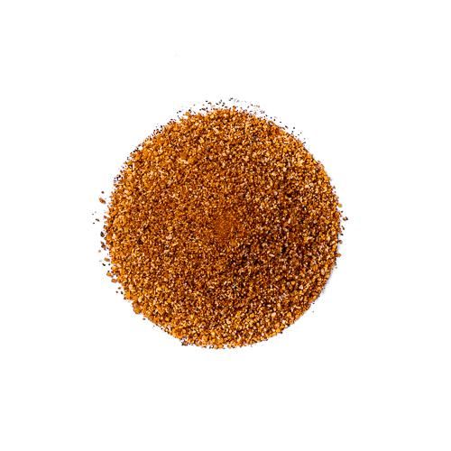 En rund haug med finmalt rødbrunt krydder, «Sucklebusters Clucker Dust BBQ Rub», er avbildet på en ensfarget hvit bakgrunn.
