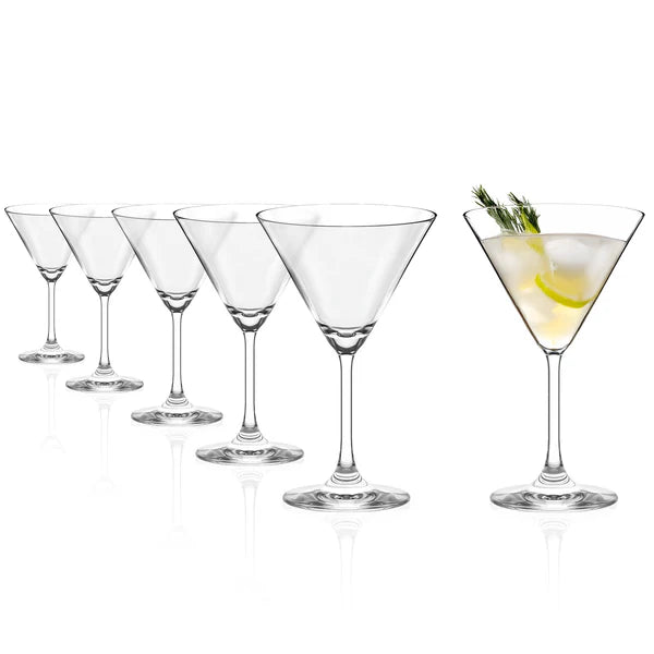 Seks Stölzle Lausits Cocktail Glass Professional 250 ml står på rekke og rad; fem av glassene er tomme, mens det siste inneholder en martini med is, sitronskive og urter - et eksempel på ekte eleganse.