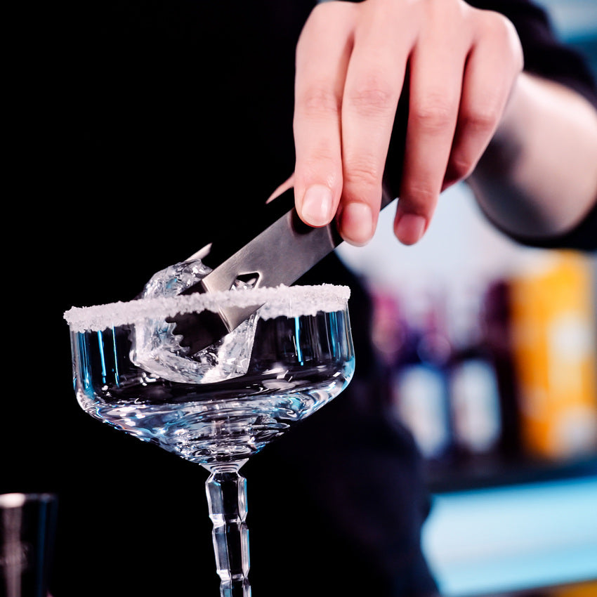 En hånd bruker Lurch Istang til å legge is i et cocktailglass med sukkerkant, og viser dermed viktige barverktøy i bruk.