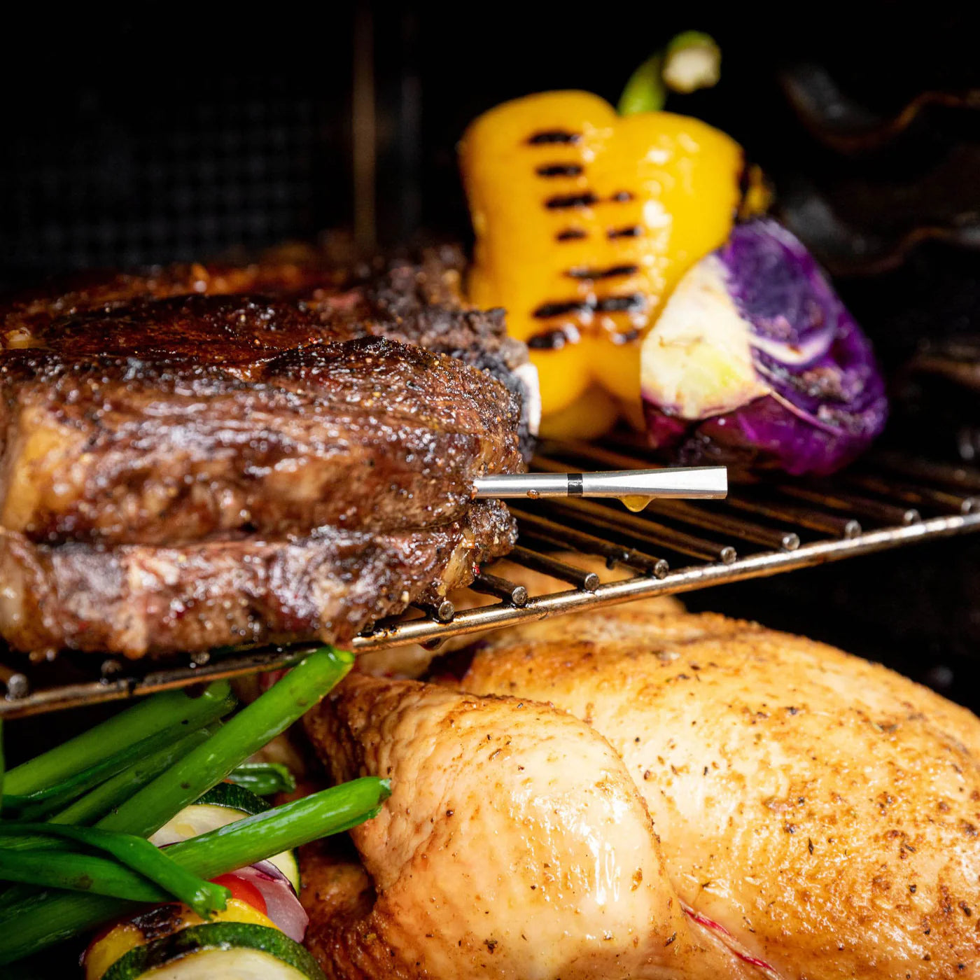 Nærbilde av grillet biff med Traeger Meater Pro - Bluetooth steketermometer, stekt kylling, grønne grønnsaker, gul paprika og lilla kål i ovn eller på grill.