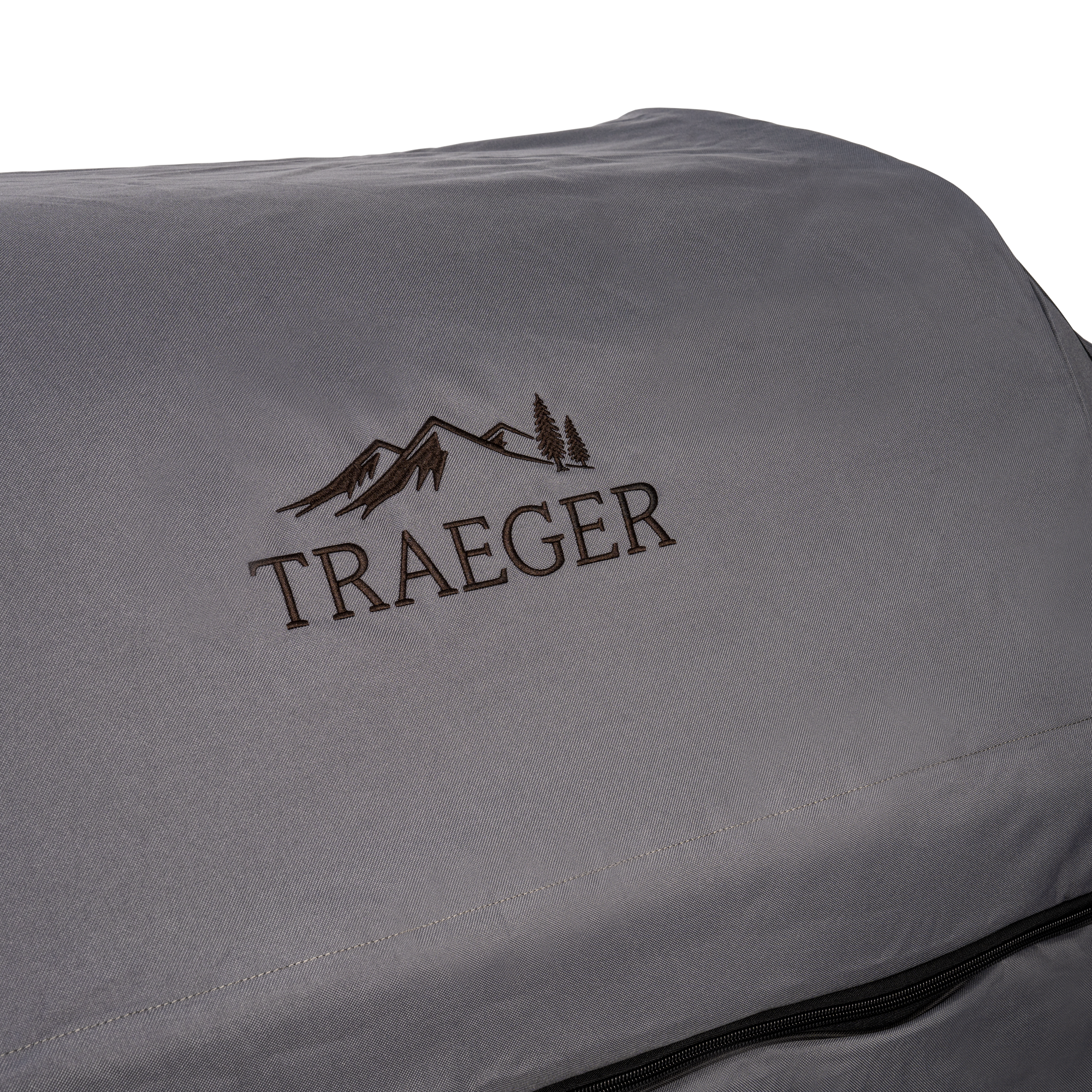 Nærbilde av Traeger Full Length Grill Cover for Timberline XL i grått, med Traeger-logoen med fjell- og tregrafikk brodert på slitesterkt stoff.