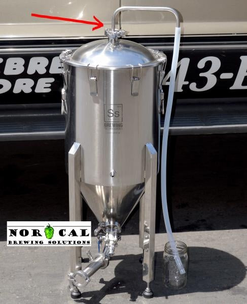 Norcal 1,5" Tri-Clamp Blow-Off Tube, laget av rustfritt stål 304, festes til en konisk fermenter i rustfritt stål utendørs i nærheten av et kjøretøy. En pil markerer lokkventilen. Logoen til Norcal-merket vises.