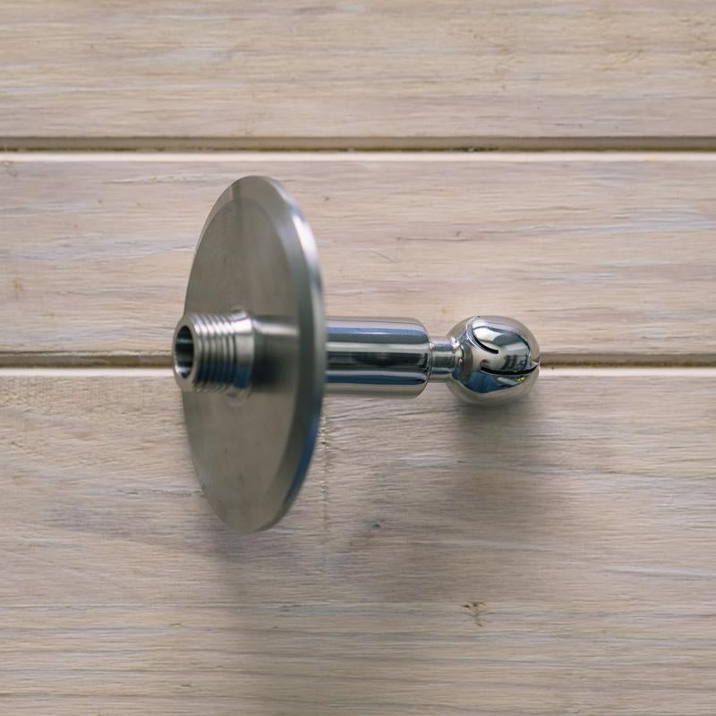 En Brewshop CIP Roterende Vaskeball 3" TC x 1/2" NPT i 304 rustfritt stål med gjengerør og avrundet ende er vist på en lys treflate.