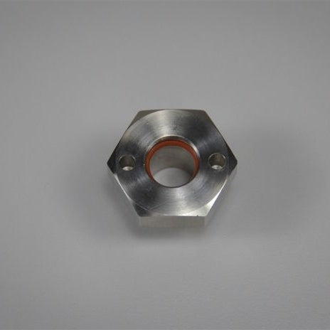 Blichmann BoilerMaker Kettle Bulkhead har en sekskantet metallkonstruksjon med et sentralt hull, oransje innerring og to mindre sidehull, vist på en grå overflate.
