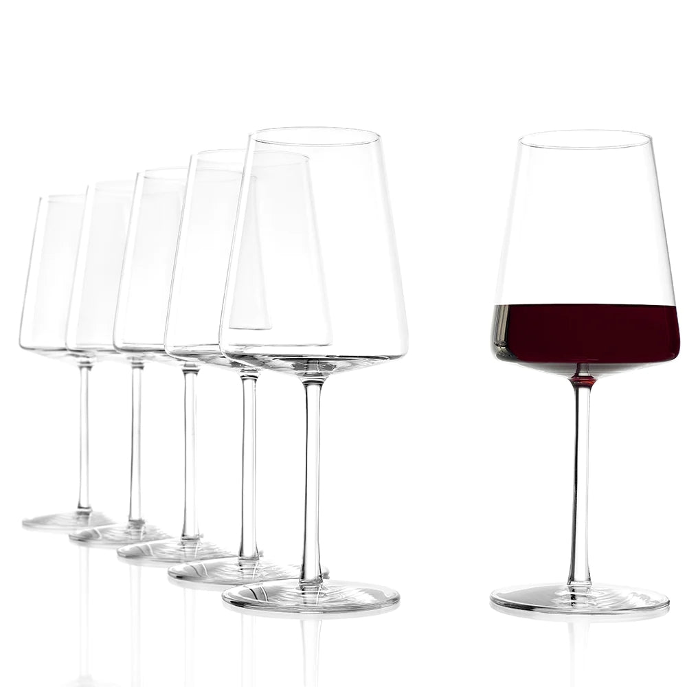 Seks Stölzle Lausitz POWER Red Wine vinglass 520 ml er stilt opp på en hvit bakgrunn; glasset lengst til høyre, som har vunnet den tyske designprisen, inneholder rødvin, mens de andre er tomme.