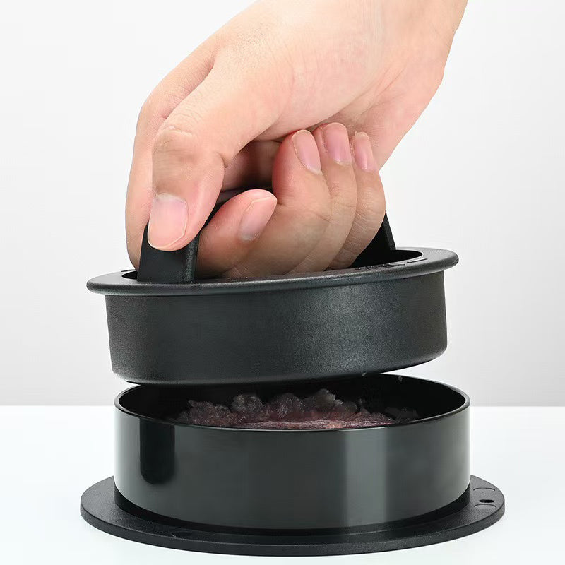 En hånd bruker «Non-Stick Burger Press» – hamburgerpressen – til å forme kjøttdeig i det nederste rommet, slik at man får perfekt formede hamburgerbiffer.
