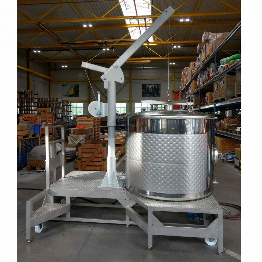 Speidel #Braumeister 1000L - Bestillingsvare er en stor tank i rustfritt stål med kranarm og plattform, perfekt for kommersiell ølbrygging, vist i en lagerhall med hyller og paller. Merkevare: Speidel.
