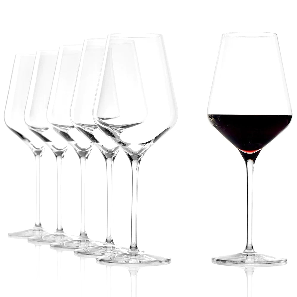 Seks QUATROPHIL Red Wine vinglass 570 ml fra Stölzle Lausits er stilt opp på rekke; fem er tomme, mens ett er fylt med rødvin.
