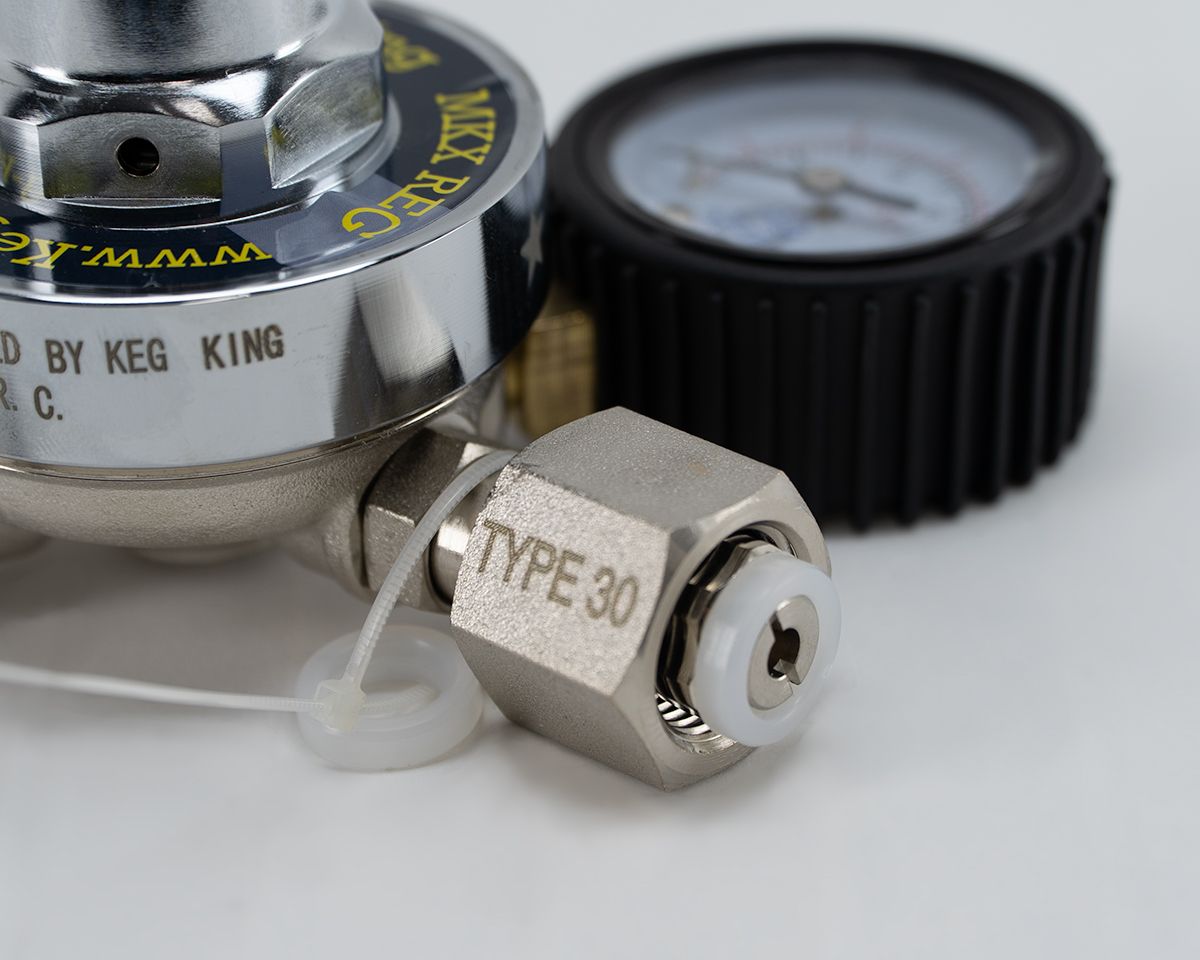 Nærbilde av Keg King Regulator MKX for CO2 med Type 30-kobling og manometer, ideell for kontroll av gasstrømmen ved hjemmebrygging, vist på en hvit overflate.