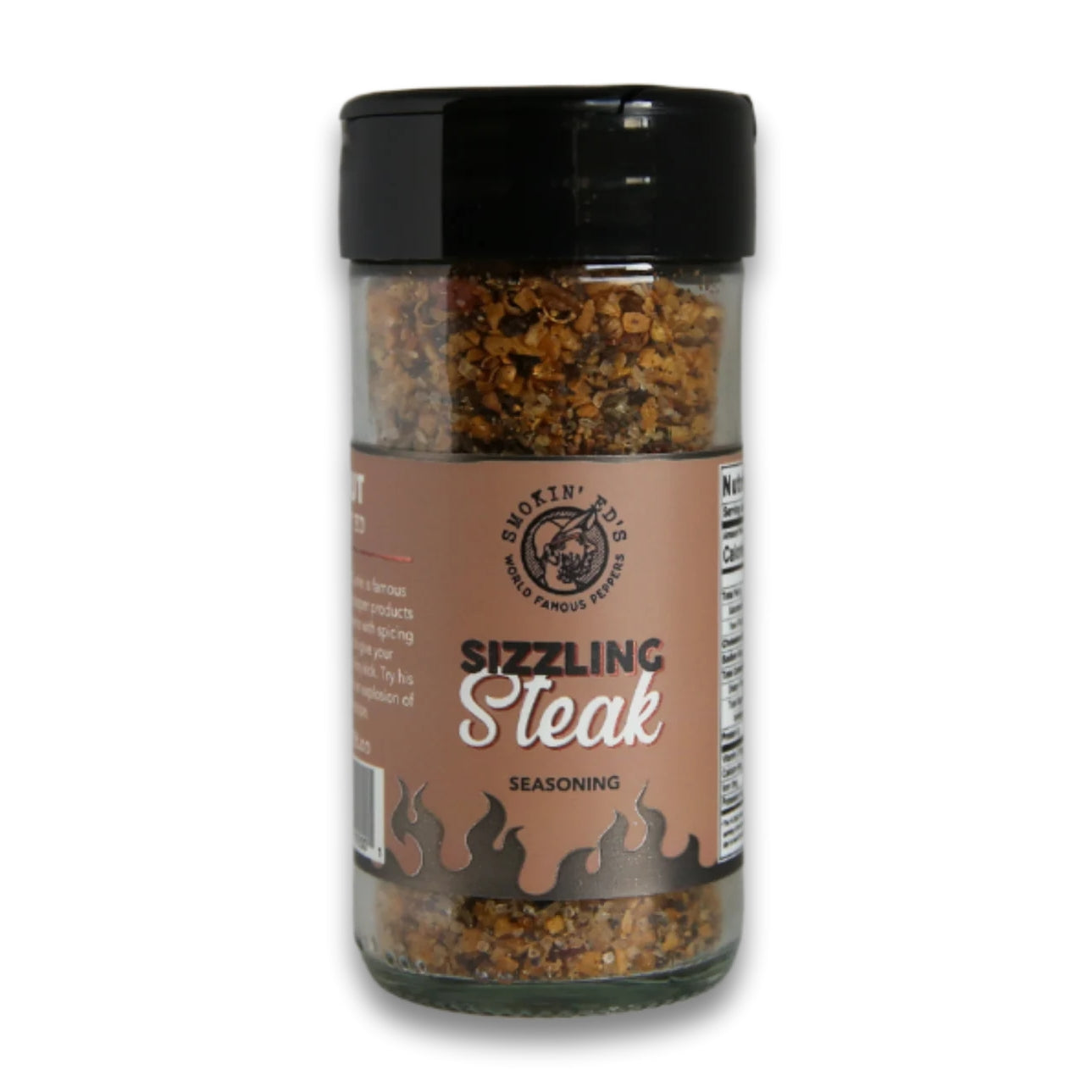 Et gjennomsiktig krydderglass merket Smokin' Ed's Sizzling Steak Seasoning fra PuckerButt Pepper Company, med svart lokk og brunfarget etikett med logo og flammegrafikk, inspirert av klassisk biffkrydder fra Montreal.