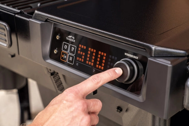 En hånd vrir på temperaturknappen på Traeger Woodridge pelletsgrillens digitale panel, som er stilt inn på 500 grader - ideelt for å oppnå autentisk vedfyrt smak.