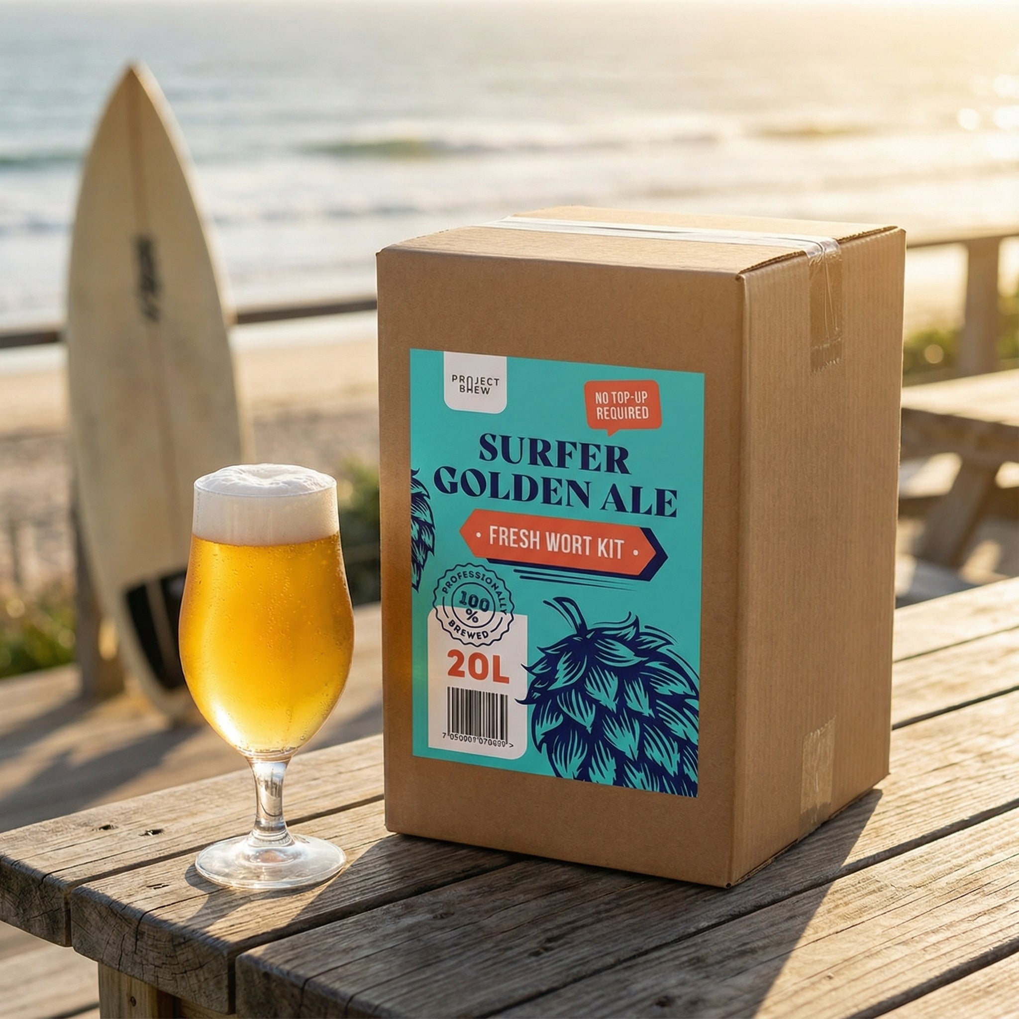 Et glass gyllent øl hviler på et trebord ved siden av en Project Brew Surfer Golden Ale - 20L Fresh Wort Kit-boks, med et surfebrett og havet synlig i bakgrunnen.
