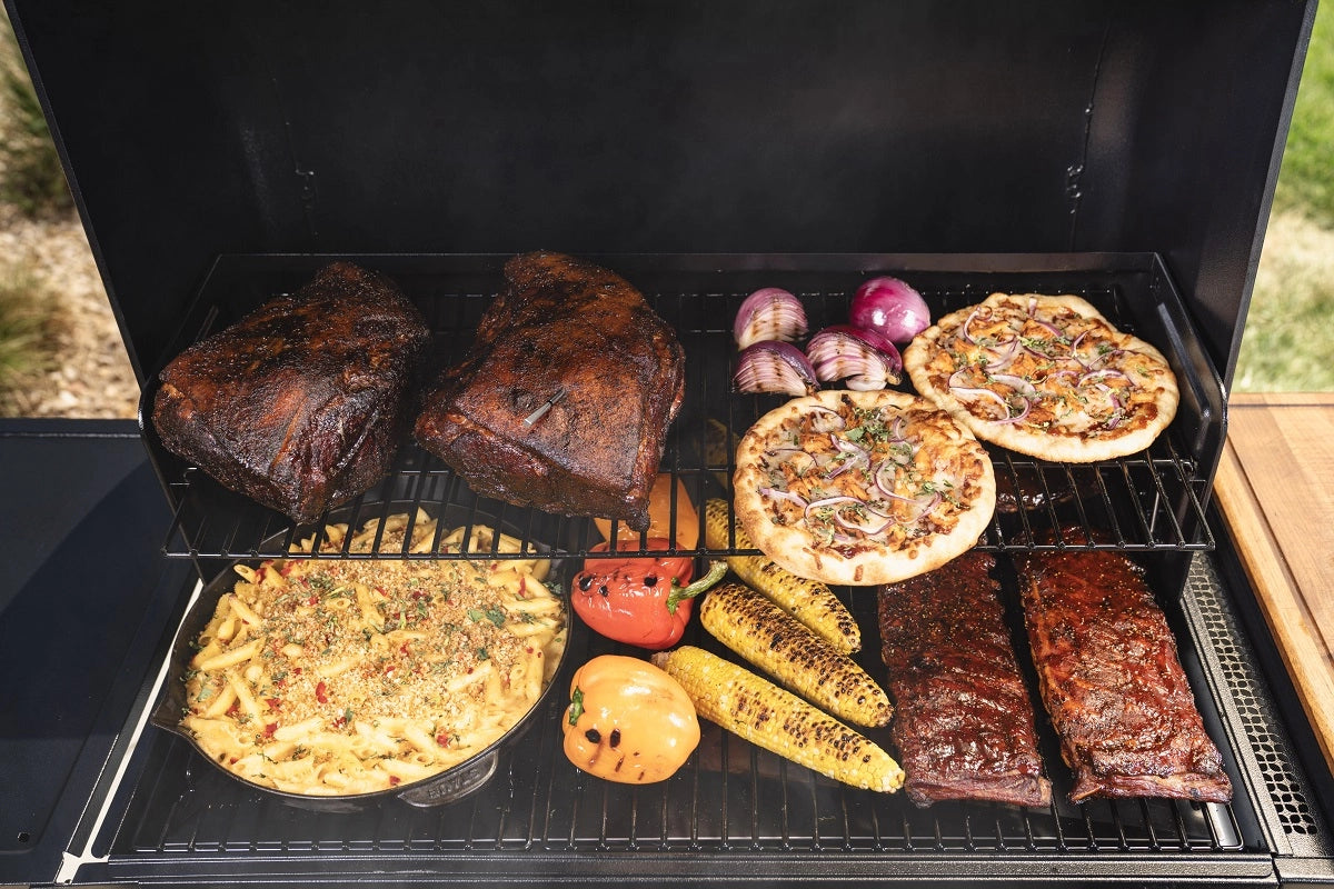 En grill fullpakket med røkt oksekjøtt, ribbe, rødløk, minipizzaer, krydret pasta, paprika og grillet mais - perfekt tilberedt på Traeger Woodridge Pro Pelletsgrill med WiFIRE-teknologi for optimal bekvemmelighet.