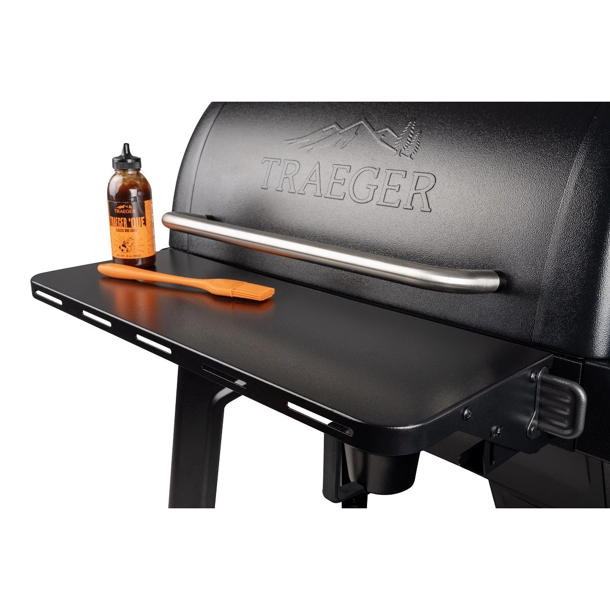 Nærbilde av en Traeger-grill med krydder og en oransje stekepensel på Traeger P.A.L. Front Shelf S, som er utstyrt med det praktiske Pop-And-Lock-systemet.