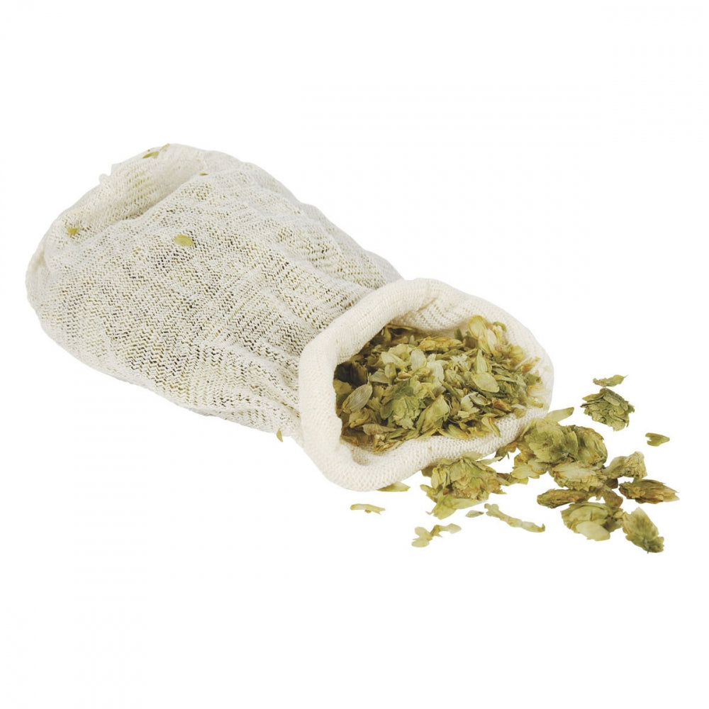 En nettingpose fylt med tørkede humleblomster, noen søler ut på en hvit overflate - perfekt for bruk med Brewferm Humleposer 10 stk, som er vaskbare og gjenbrukbare.