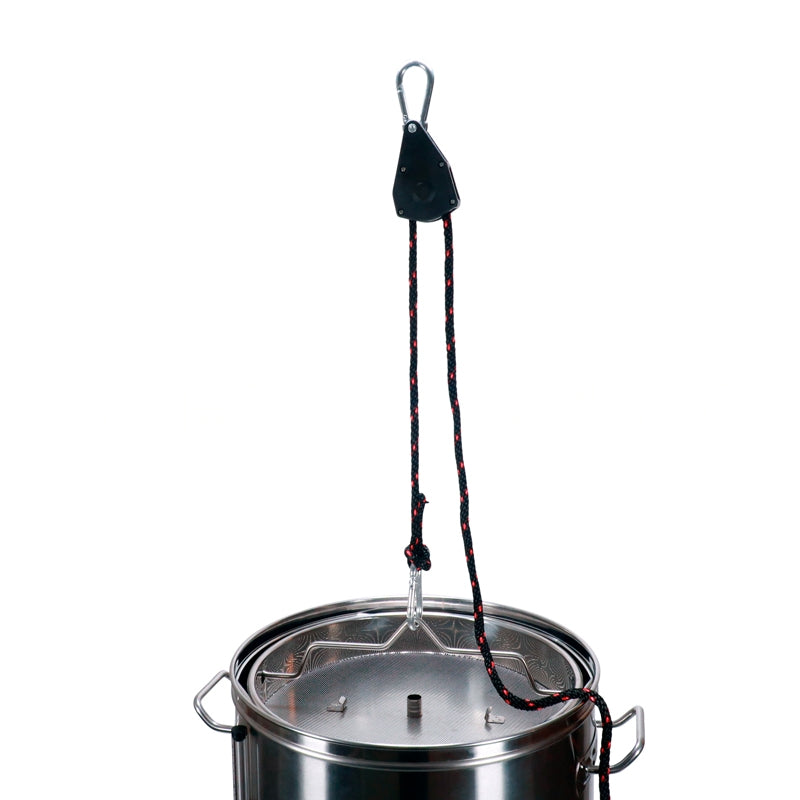 Brewolution Talje med tau og karabinkroker - 113 kg, med et 2 meter langt svart og rødt tau, er festet til lokket på en gryte i rustfritt stål.