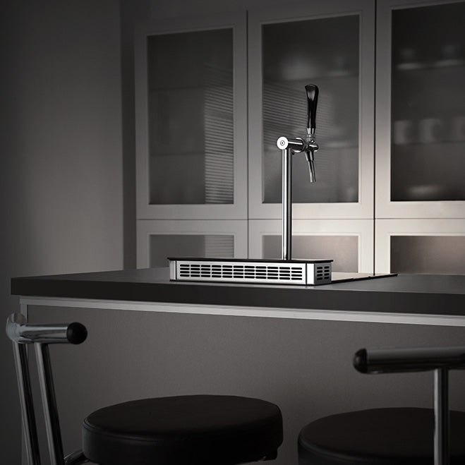 Et Lindr PYGMY Pro Kitchen øltappsystem er installert på en kjøkkenøy med to barkrakker foran og skap med glassfront bak - et ideelt oppsett for å vise frem kvaliteten på Lindrs moderne tappetårn for kjøkkenet ditt.