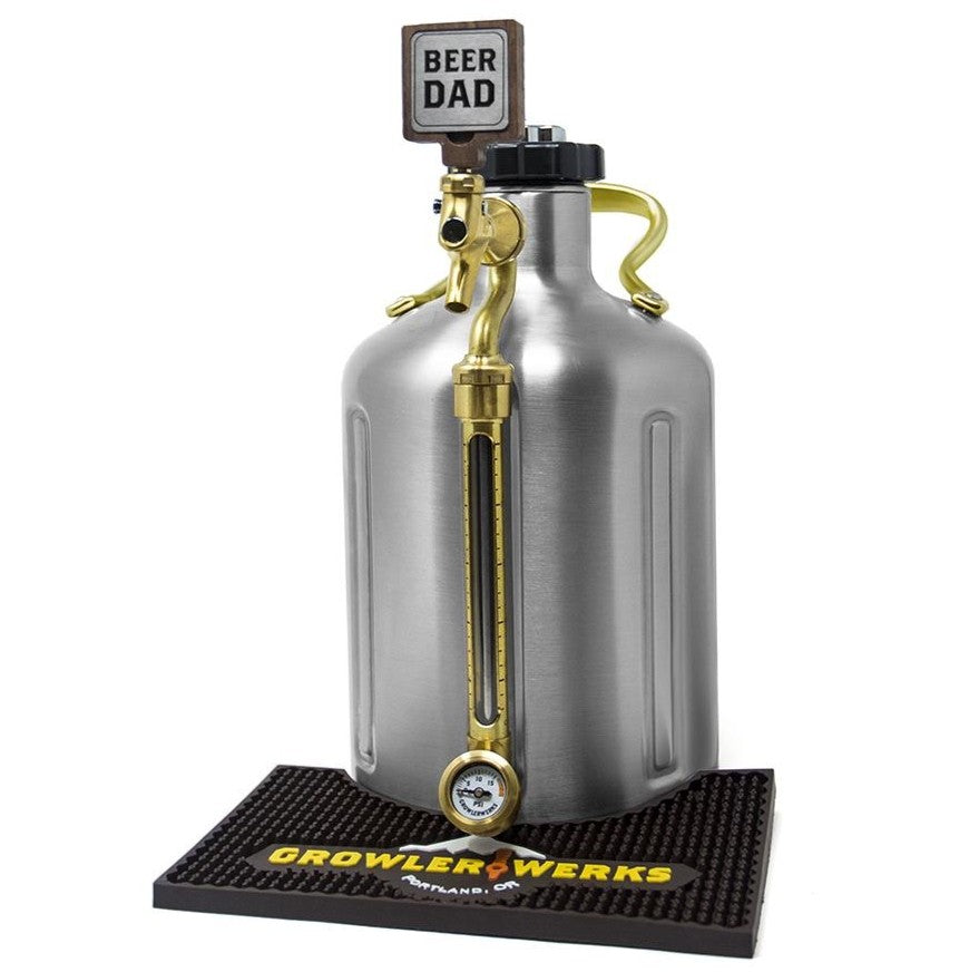 En ølflaske i rustfritt stål med tappekran, trykkmåler og Beer Dad Tap Handle - Håndtak til uKeg fra GrowlerWerks er utstilt på en merkevarematte og leveres i en skumbelagt eske for ekstra beskyttelse.
