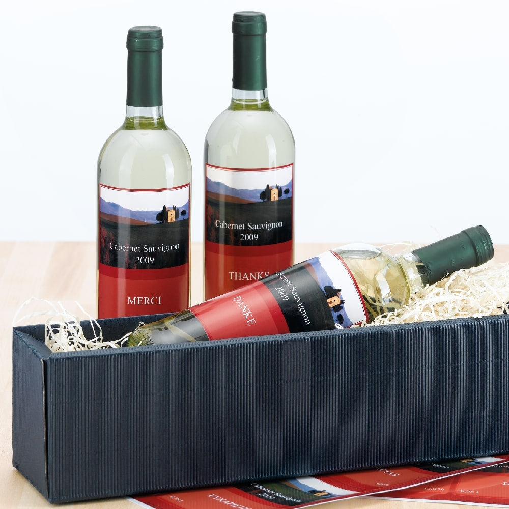 Tre hvitvinsflasker - to stående og én liggende i en sort stråforet gaveeske - er utstyrt med Herma flaske etiketter 90 x 120 mm fra Herma, som viser Cabernet Sauvignon 2009 på hver flaske.