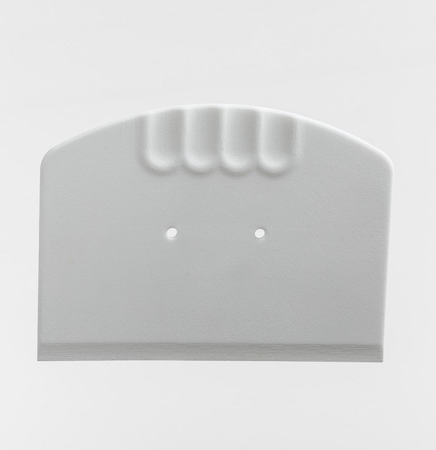 Enolandia Ostemassekutter er en hvit plastskrape med buet topp, to små hull i midten og tre fingerfordypninger for bedre grep.