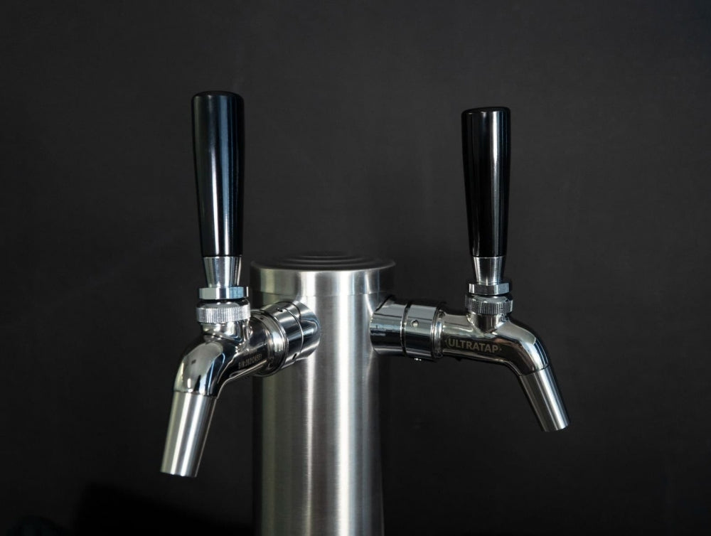 Nærbilde av Keg King FasTap Font Kit - Tappetårn sett med 2 kraner, et dobbelt tappesystem i rustfritt stål med svarte håndtak, vist mot en elegant svart bakgrunn.