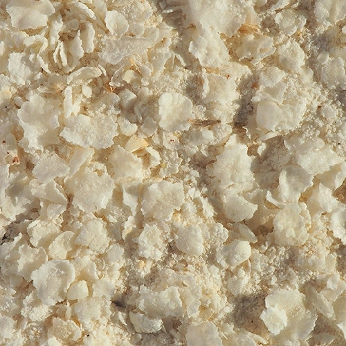 Nærbilde av Crisp Malting Flaked Torrefied Rice, flaket ris, 100G-hvite, tørre flak med lavt gluteninnhold spredt på en flat overflate.