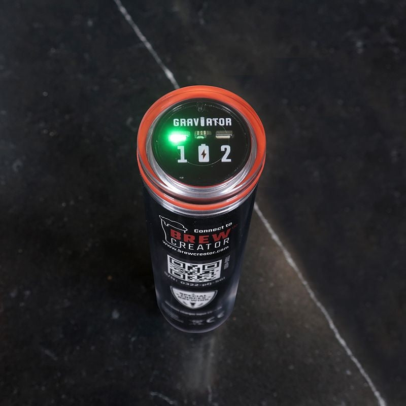 En sylindrisk Graviator - WiFi hydrometer og termometer fra Brewolution, med grønt lys, står oppreist på en mørk flate. På siden vises en QR-kode, BrewCreator-tekst og forslag til trådløs bryggesporing.