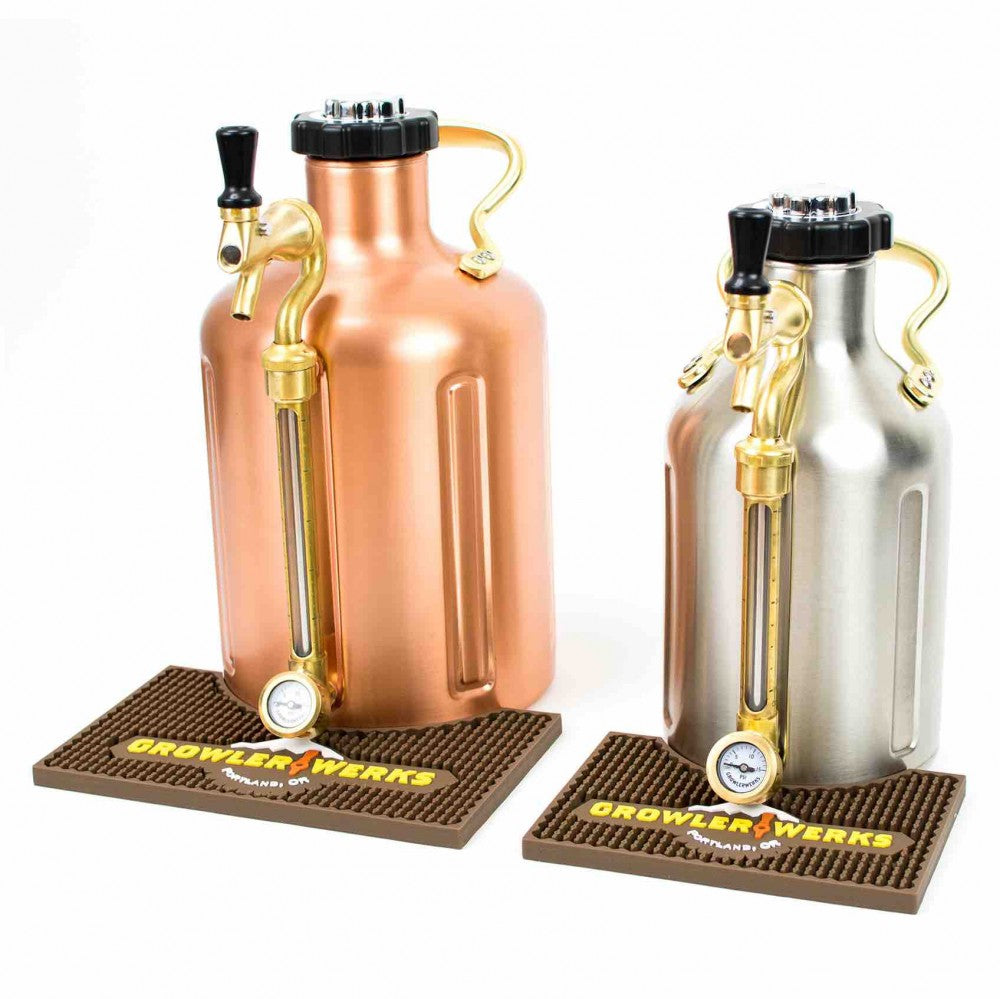To uKeg 64 oz growlers i metall under trykk - en i kobber og en i rustfritt stål - med tappehåndtak står på en GrowlerWerks uKeg 64 Bar Mat, vist mot en hvit bakgrunn.