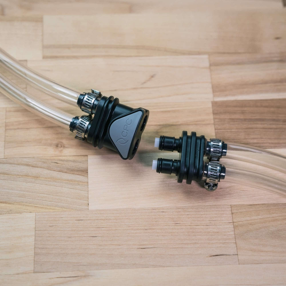 To klare plastrør med svarte Ss Brewtech FTSS One Quick Disconnect Kit-fittings og metallklemmer hviler på en treflate.