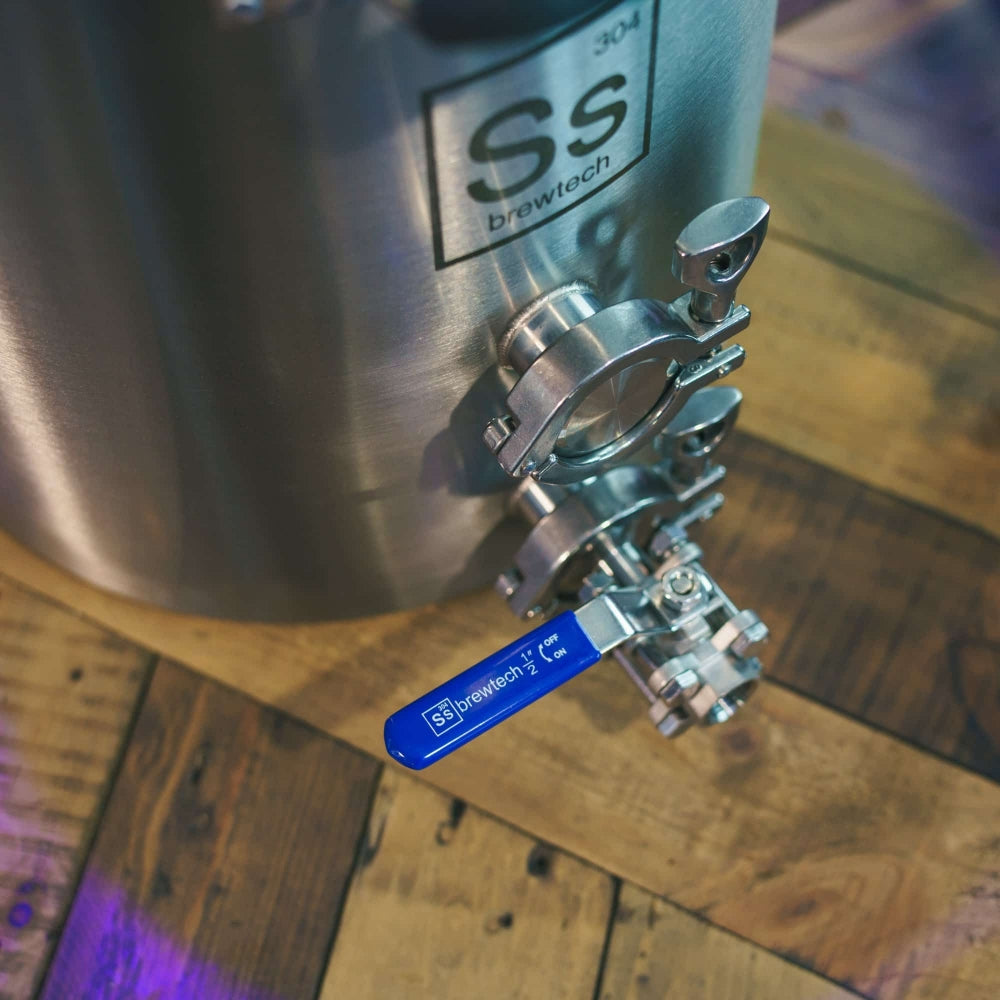 Ss TC Brew Kettle 189L (50 gal) Bryggekjele fra Ss Brewtech har varemerkets logo, en ventil med blått håndtak og en tri-clamp-porter festet med metallklemmer, utstilt på en overflate av tre.