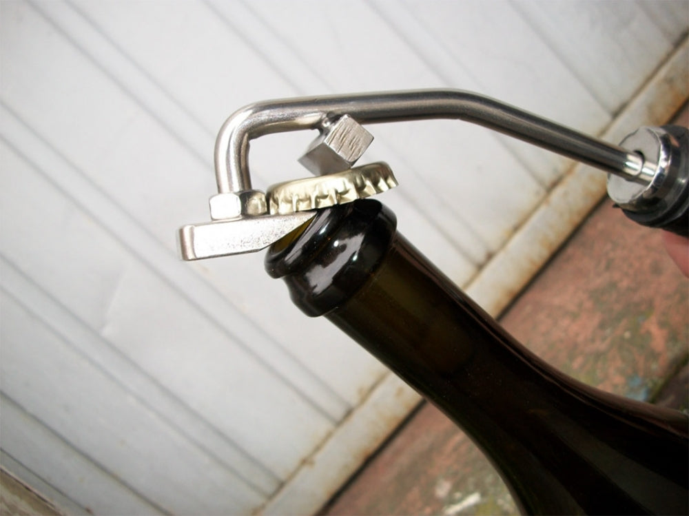 Nærbilde av en Spagni degorgerger / degorgeringsjern for musserende vin og cider som fjerner metallkorken fra en mørk glassflaske med cider.