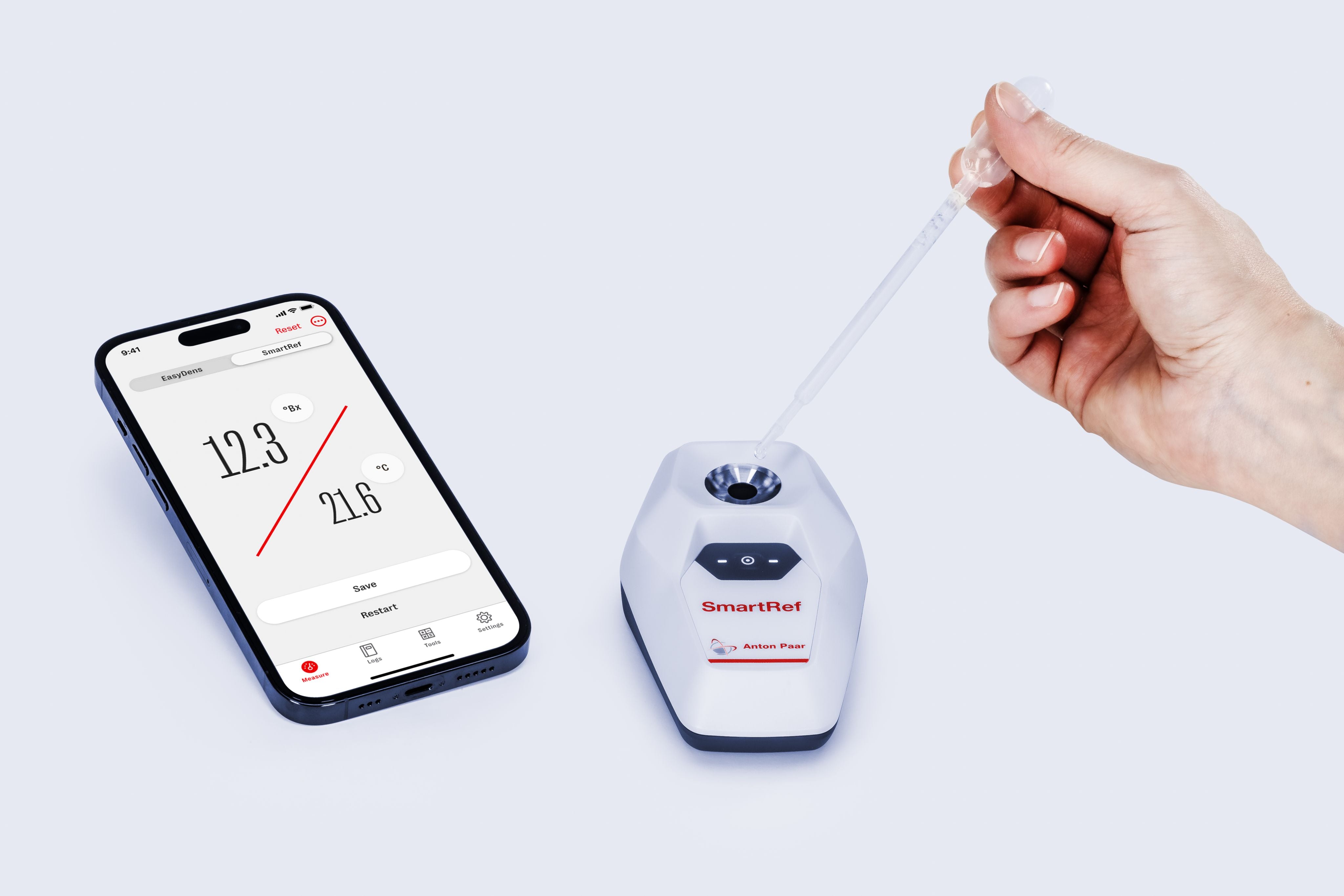 En hånd bruker en pipette til å tilsette væske til et Anton Paar SmartRef Digitalt Refraktometer for ølbrygging, mens en smarttelefon viser resultatene av vørter- og alkoholkorreksjon.