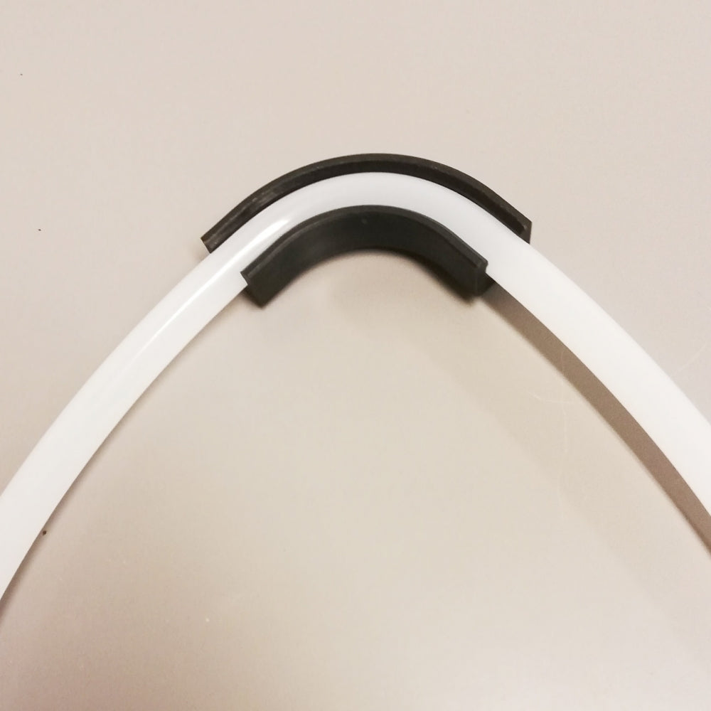 To buede, hvite plaststenger med sorte gummihetter, som ligner på John Guests Flow Bend Clip 3/8", plasseres på en lys overflate.